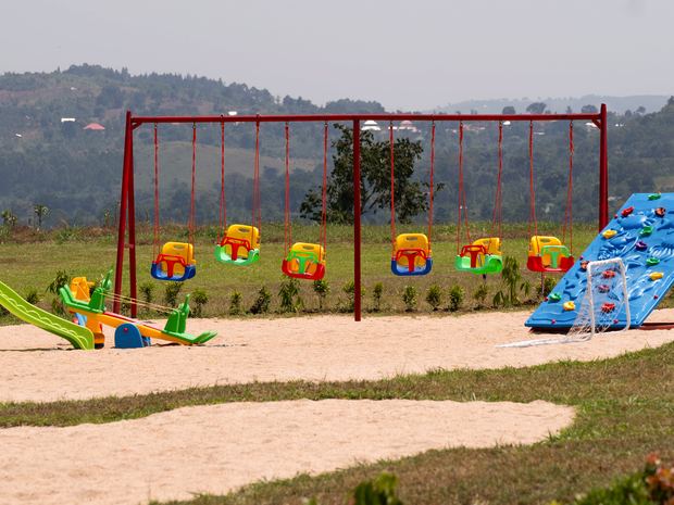 Der Spielplatz mit Schaukelreihe, Wippe, Rutsche und Kletterwand vor der Hügellandschaft