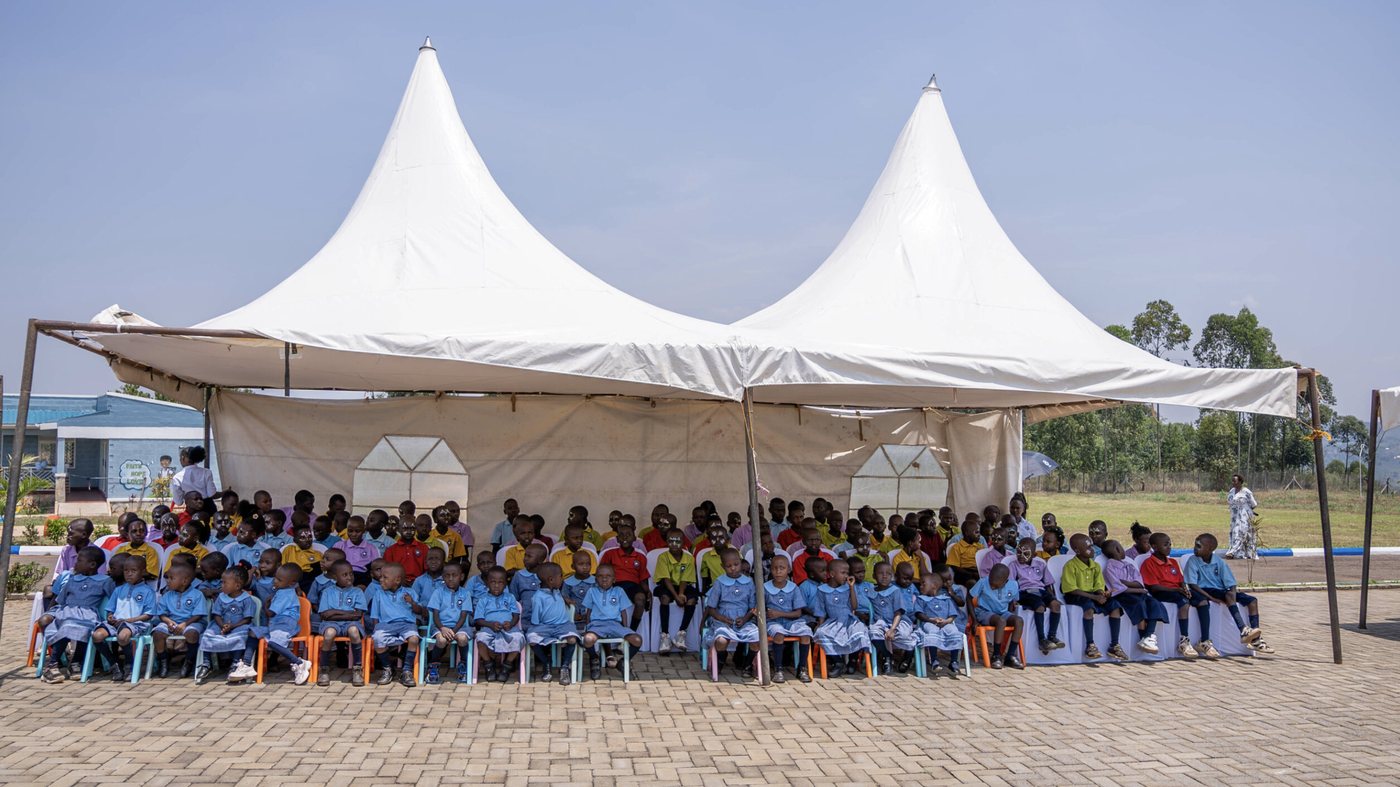 Alle Kinder des Kindergartens sitzen zum Gruppenfoto unter dem weißen Zeltdach