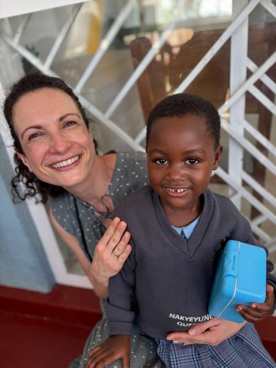 Teammitglied der Jona Foundation mit einem lachenden Mädchen in Schuluniform